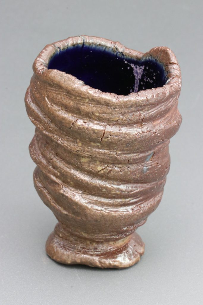 Manganese blue glaze is picking up a purple drip in the back of the cup. This cup was wadded on its backside and placed in a heavily reduced part of the kiln.